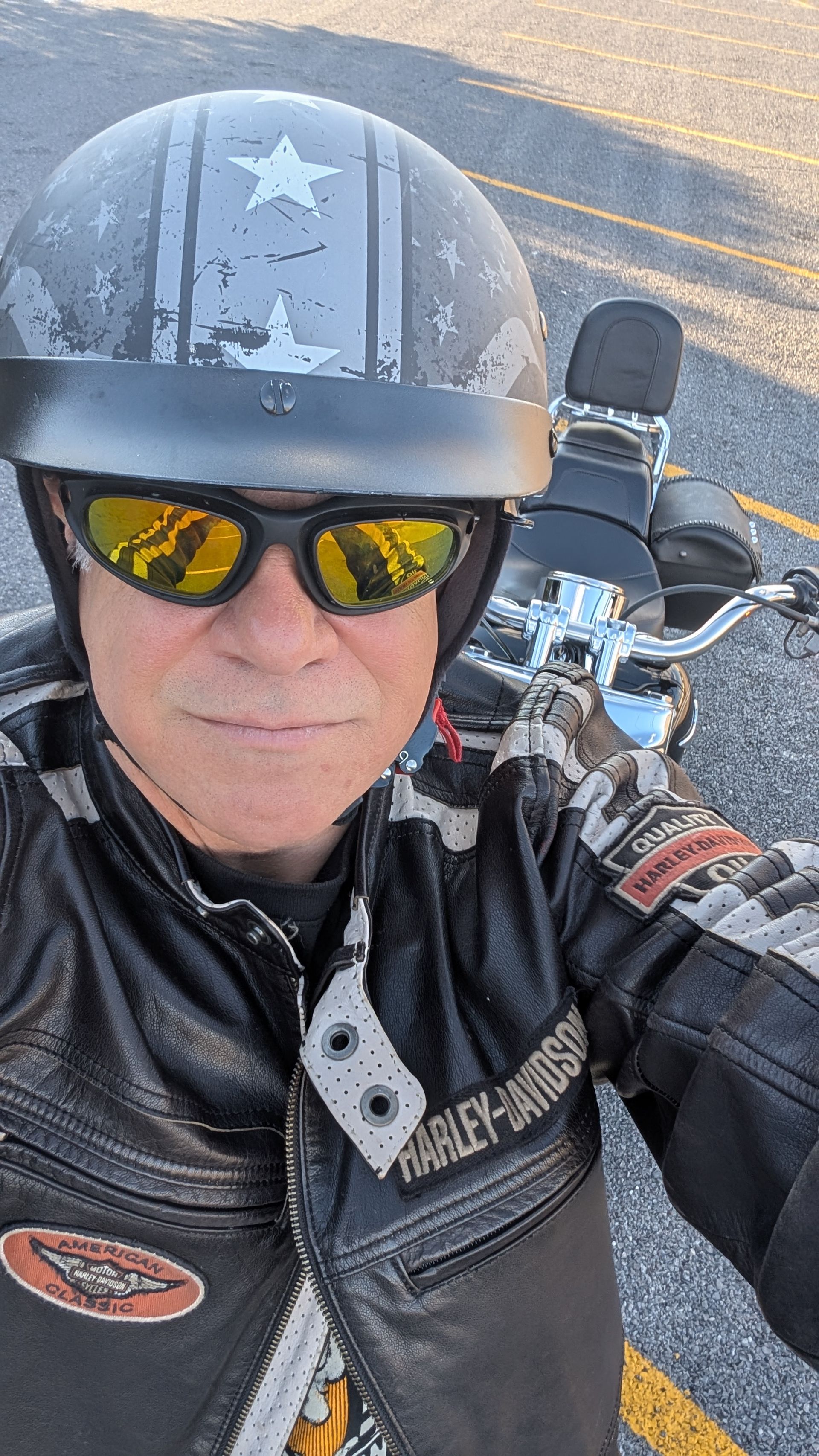 Man wearing a motorcycle helmet and sunglasses on a bike, with a Harley-Davidson jacket.