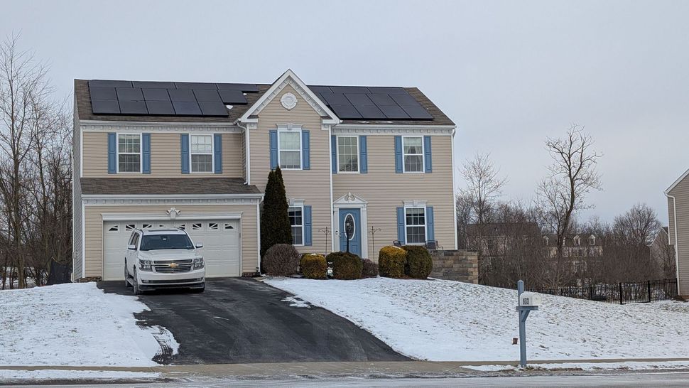Snowy suburban house with a driveway, parked SUV, and bare winter trees