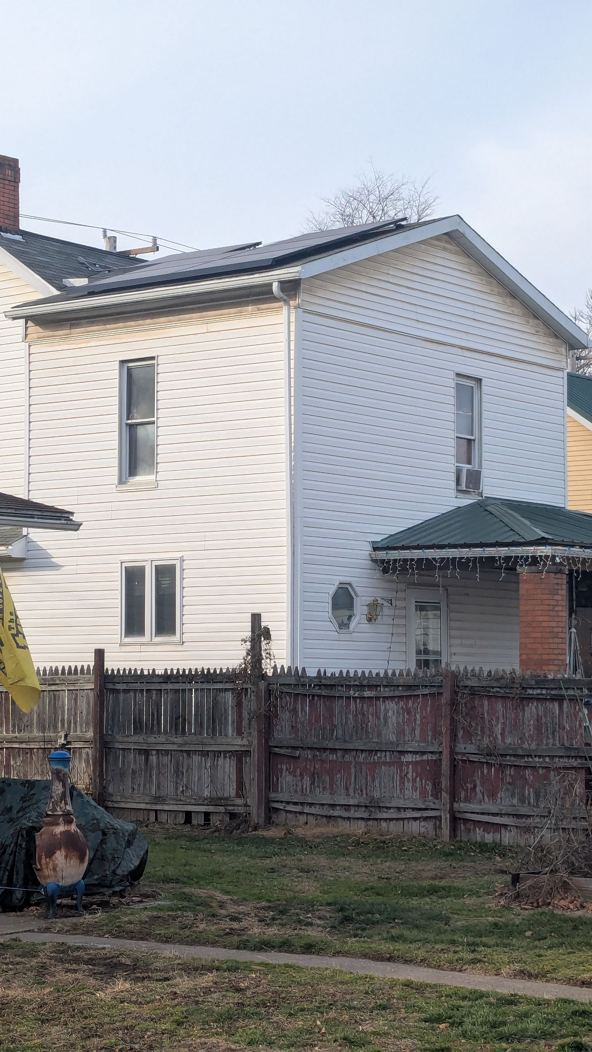 White two-story house with a fenced yard and solar panels on the roof.