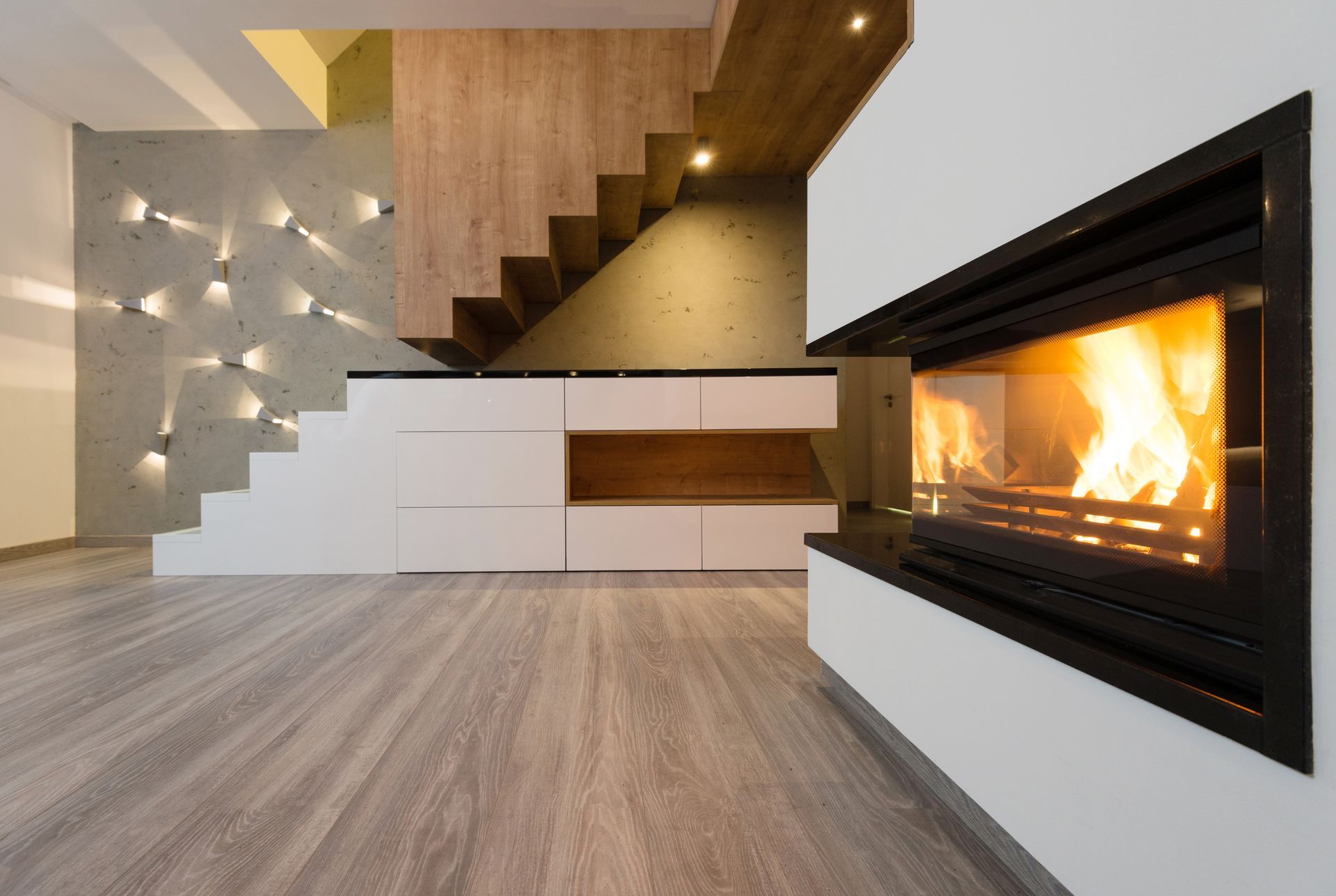 Un salon avec une cheminée et un escalier en arrière plan.