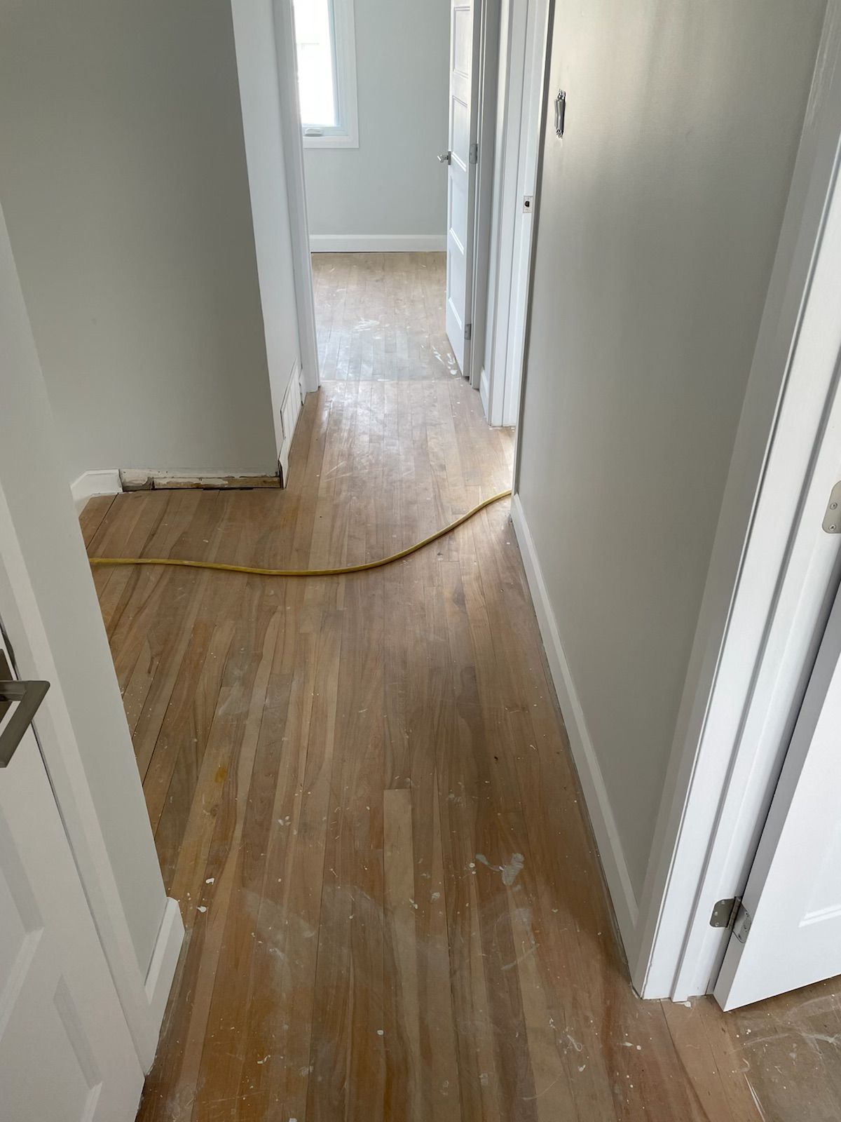 A hallway with hardwood floors and white walls in a house.