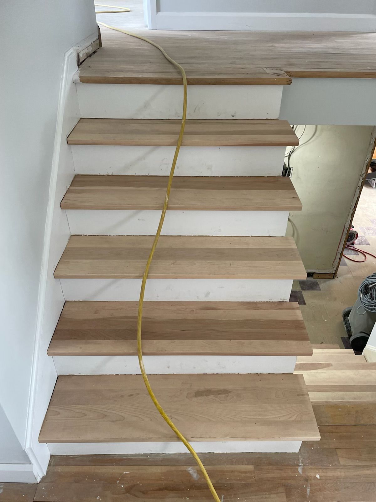 A wooden staircase with a yellow cord hanging from it.