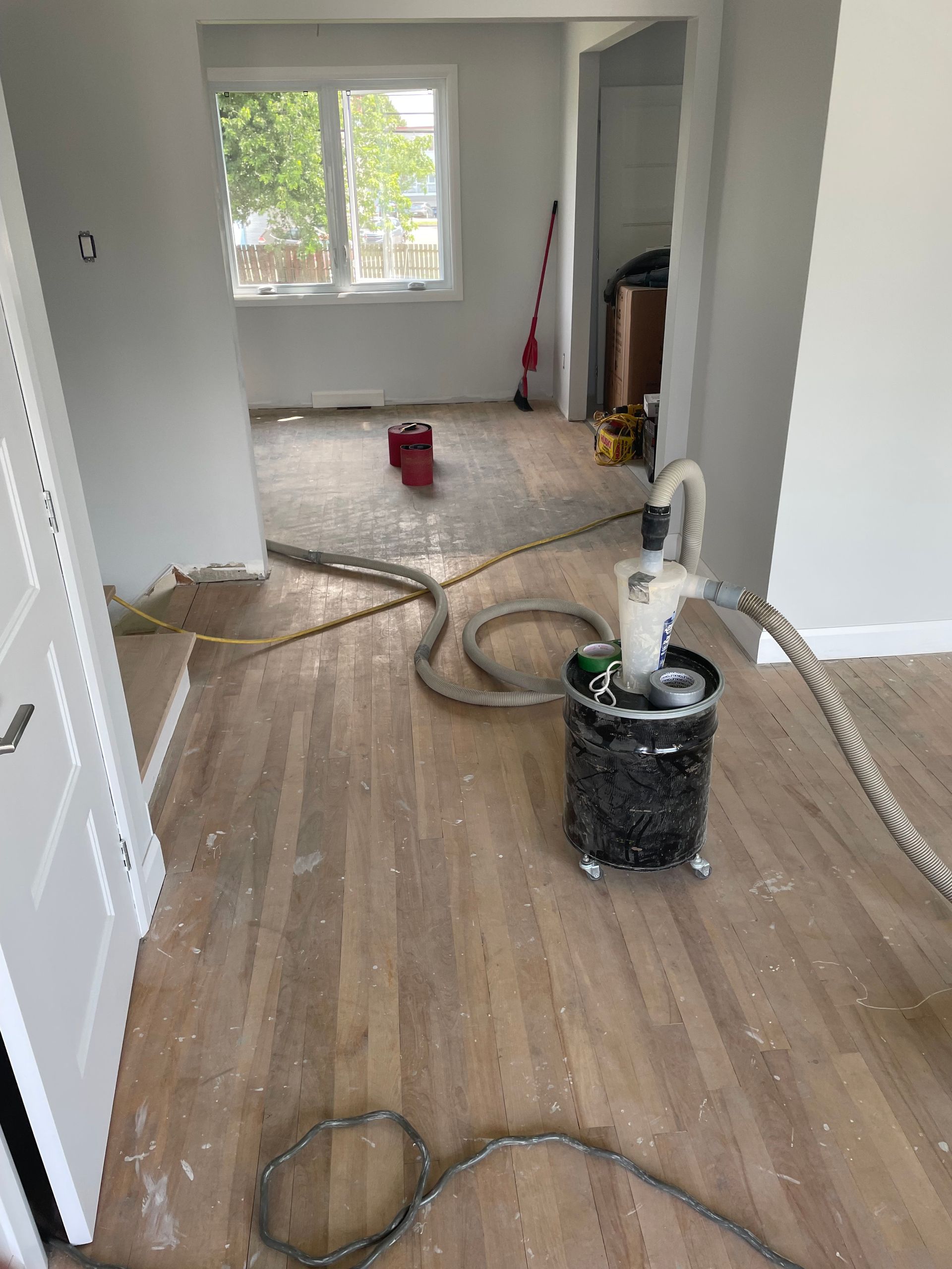 Ponçage du parquet ; système d’aspiration des poussières visible. Rénovation intérieure en cours.