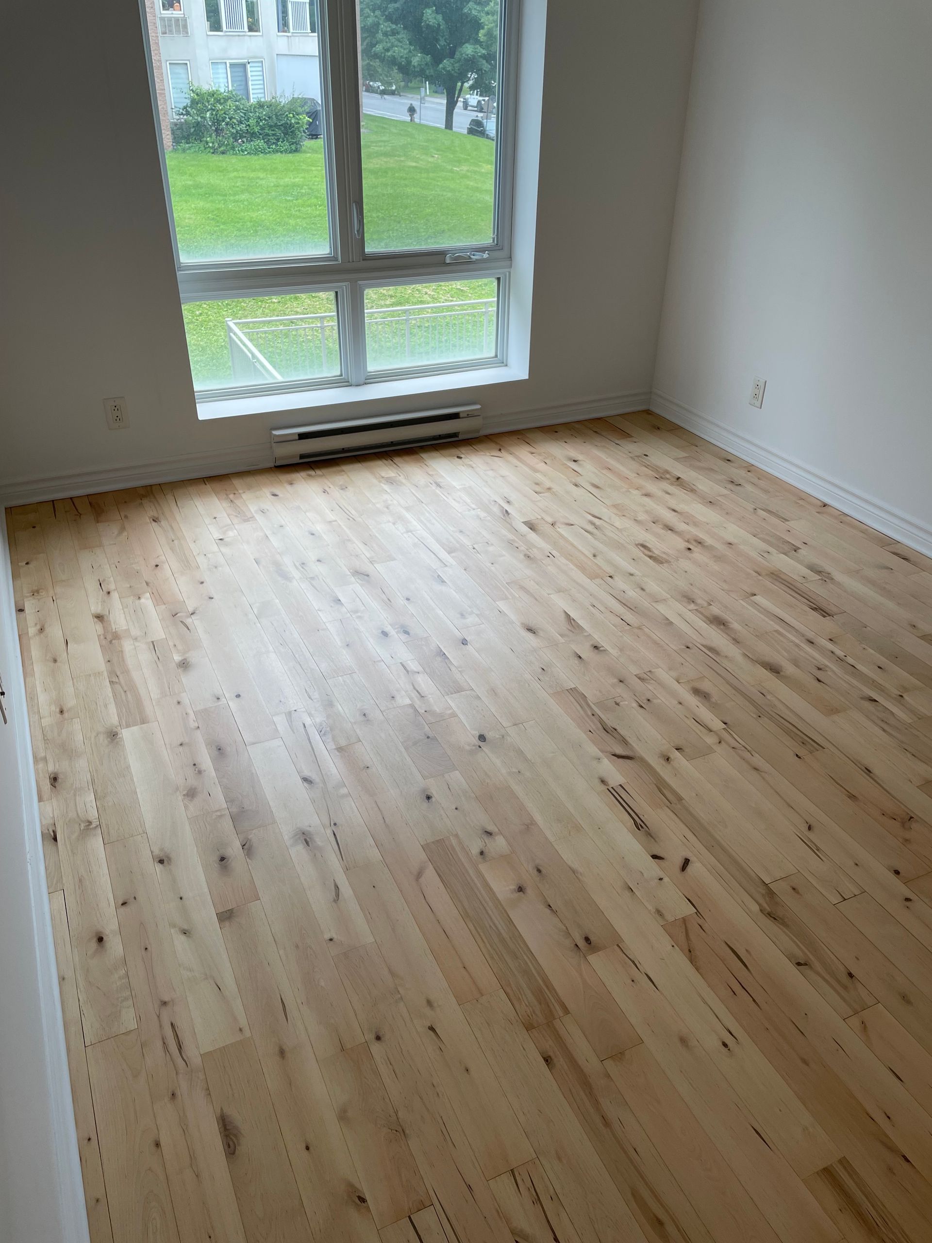 An empty room with a wooden floor and a window.
