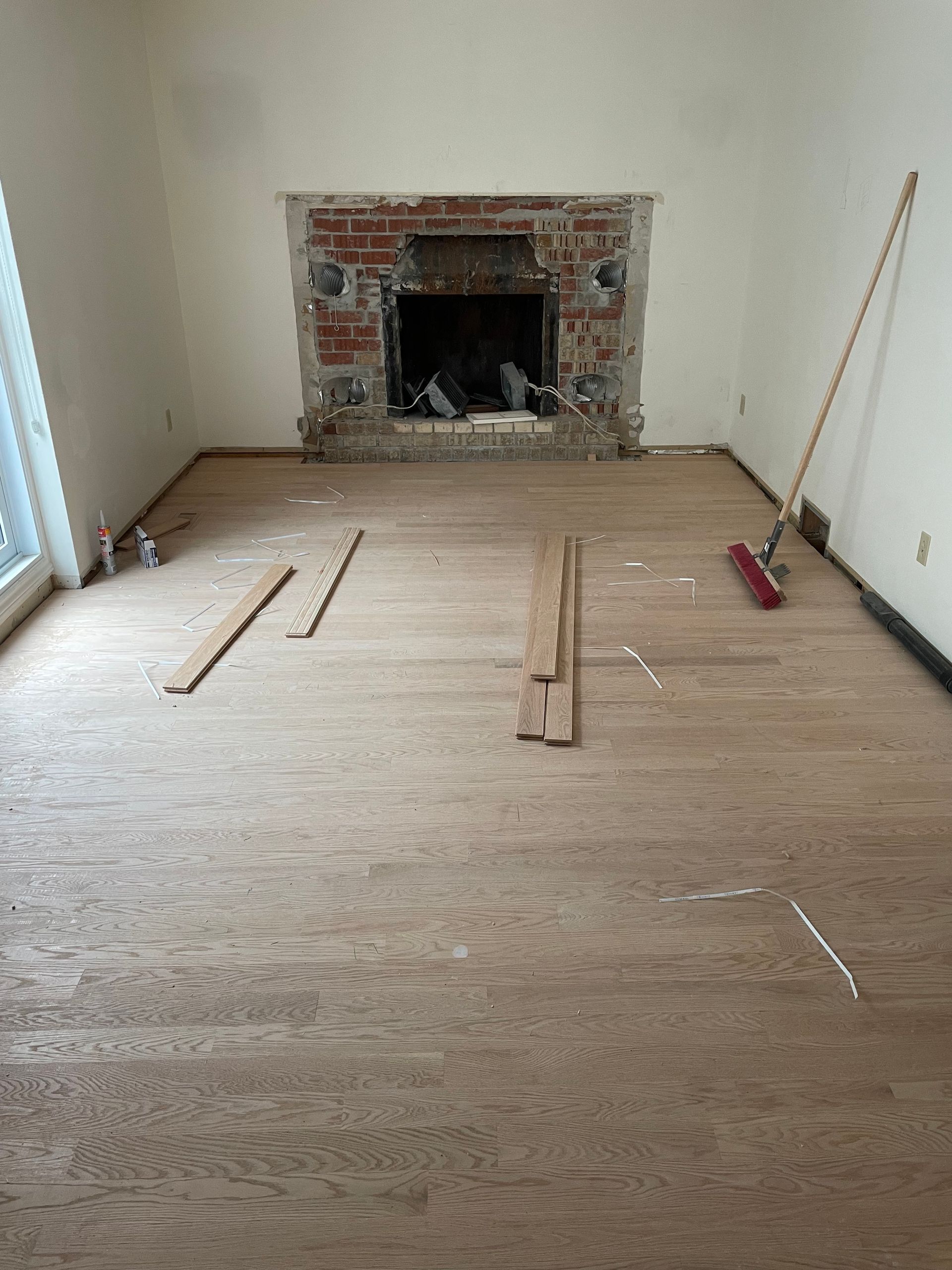 A living room with a fireplace and a broom on the floor.
