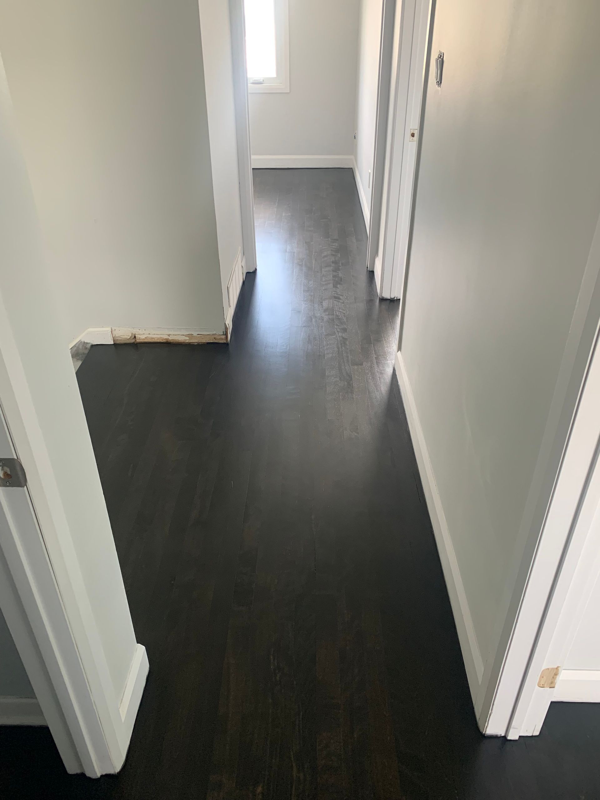 A hallway with a black floor and white walls.