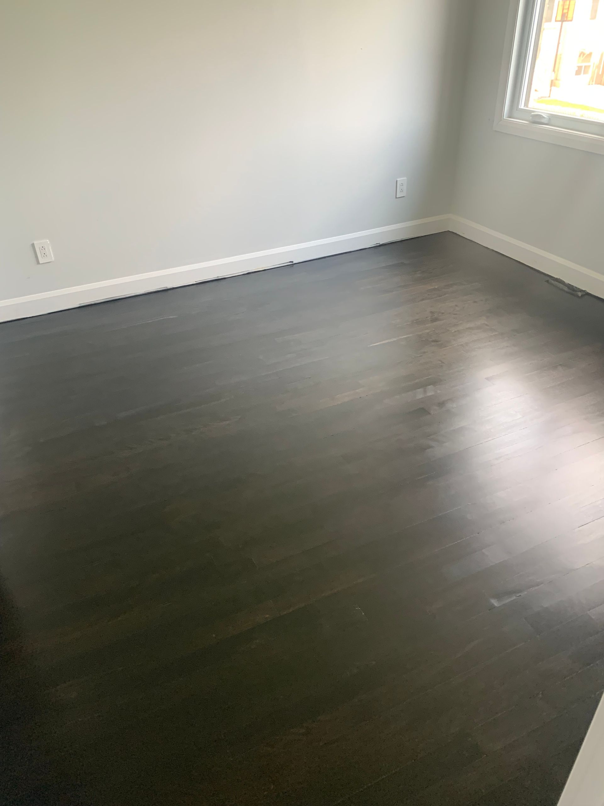 A bedroom with a dark wooden floor and white trim.