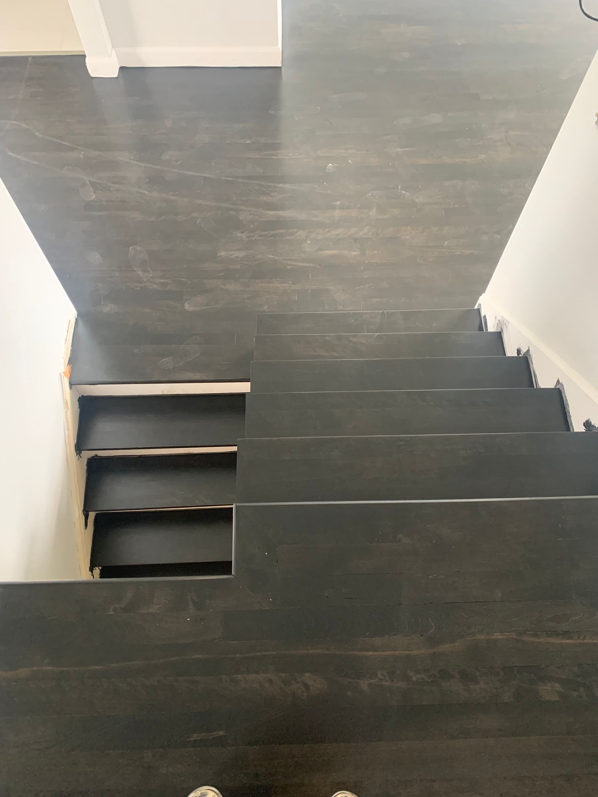 A black staircase with a wooden floor in a house.