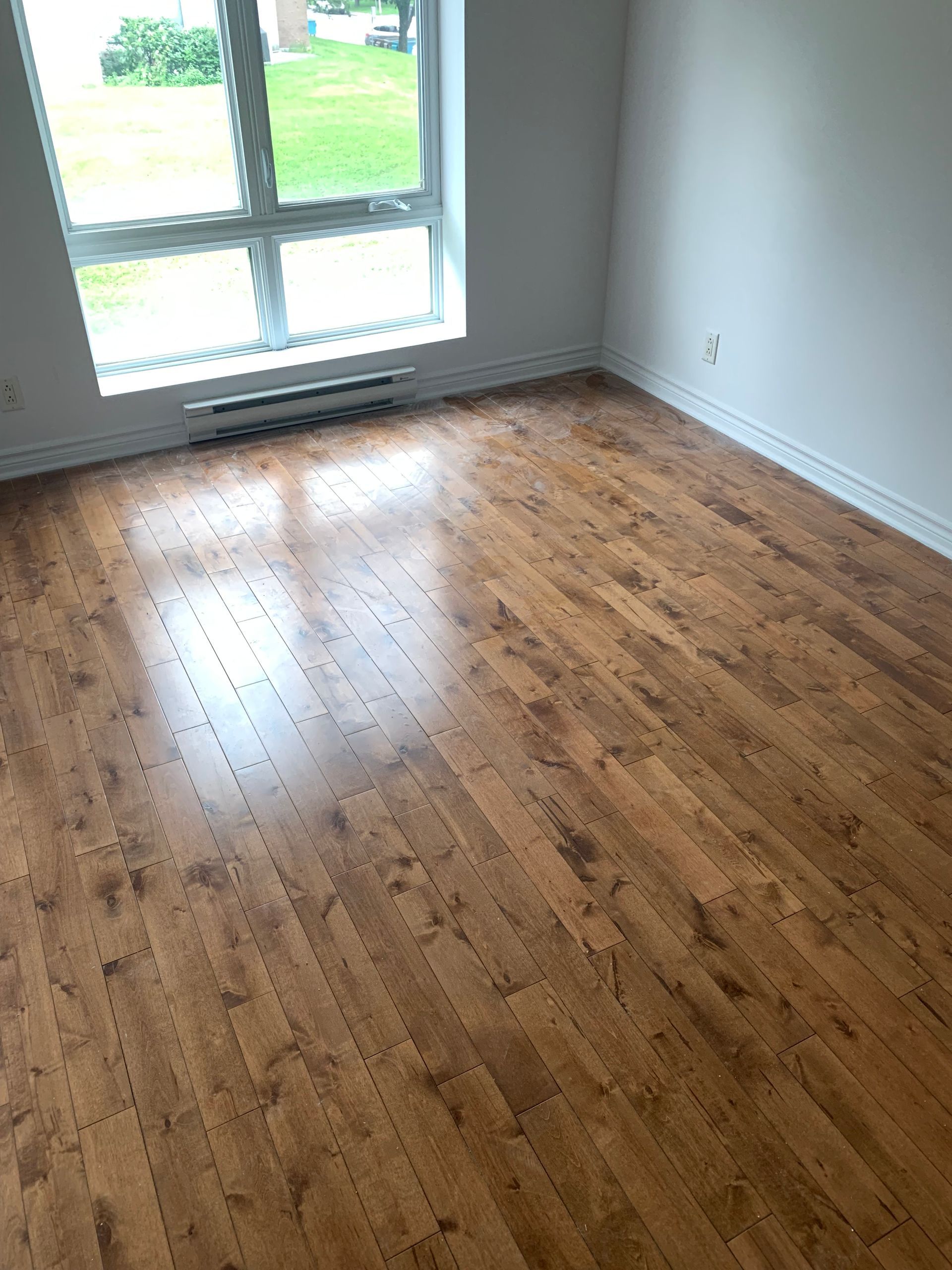 An empty room with hardwood floors and a window.