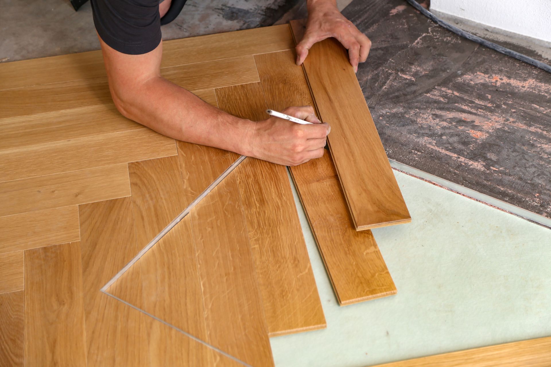 Un homme mesure un morceau de bois avec une règle.
