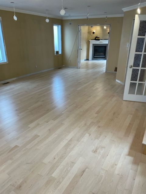 Dans cette maison, le sol est en parquet clair, les murs sont beiges et une cheminée est visible dans la pièce voisine.