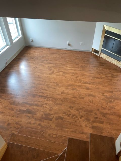 An empty living room with hardwood floors and a fireplace