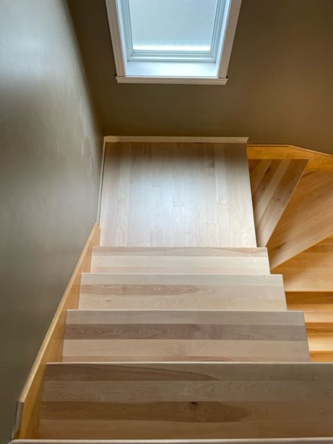 The stairs are made of wood and there is a window above them.