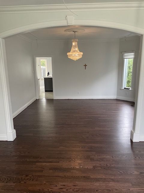 Un salon avec parquet et un lustre suspendu au plafond.