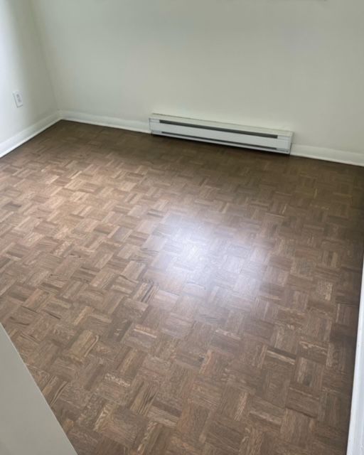An empty room with a wooden floor and a white wall.