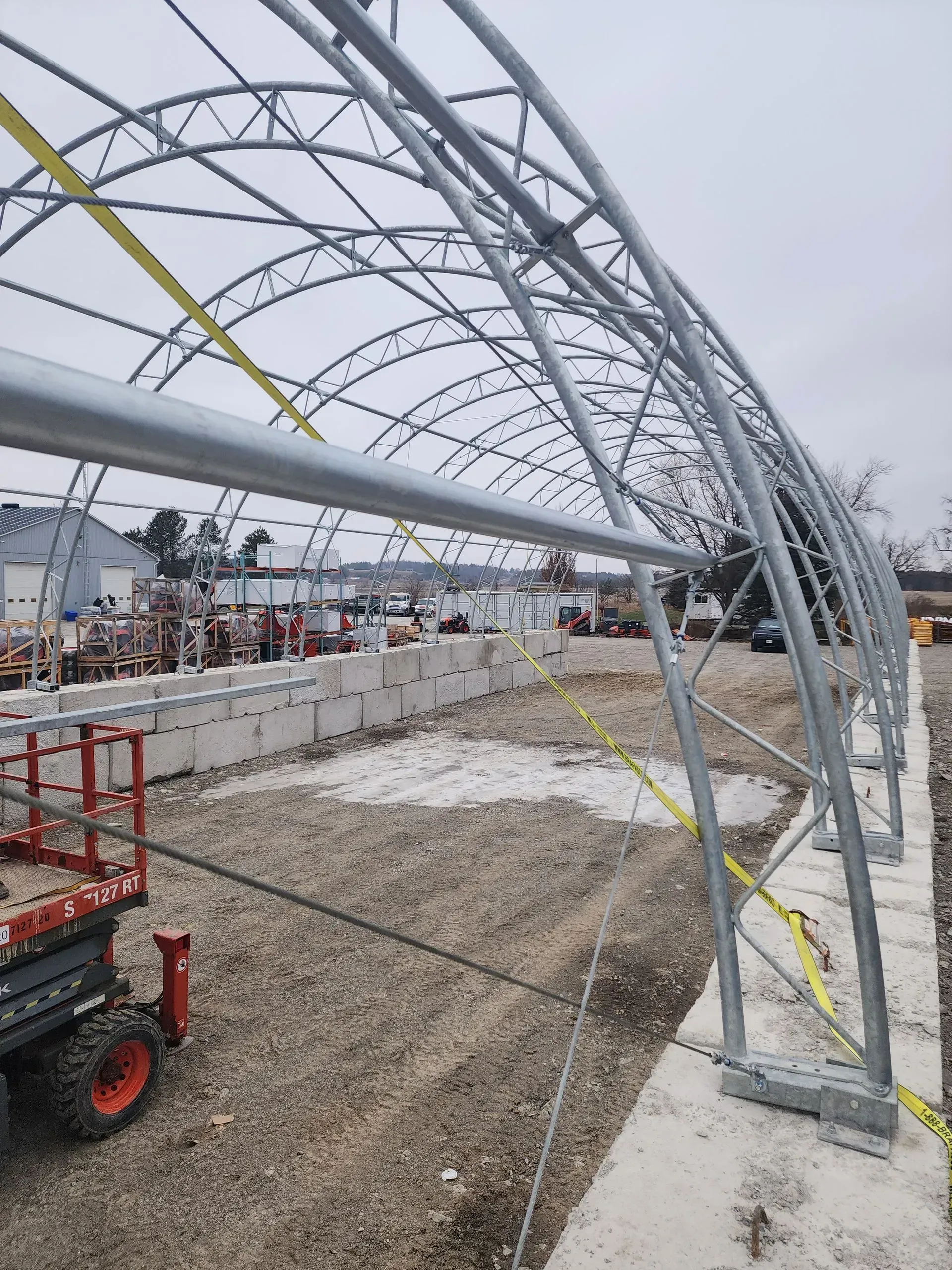 A large metal structure is being built in a dirt field.