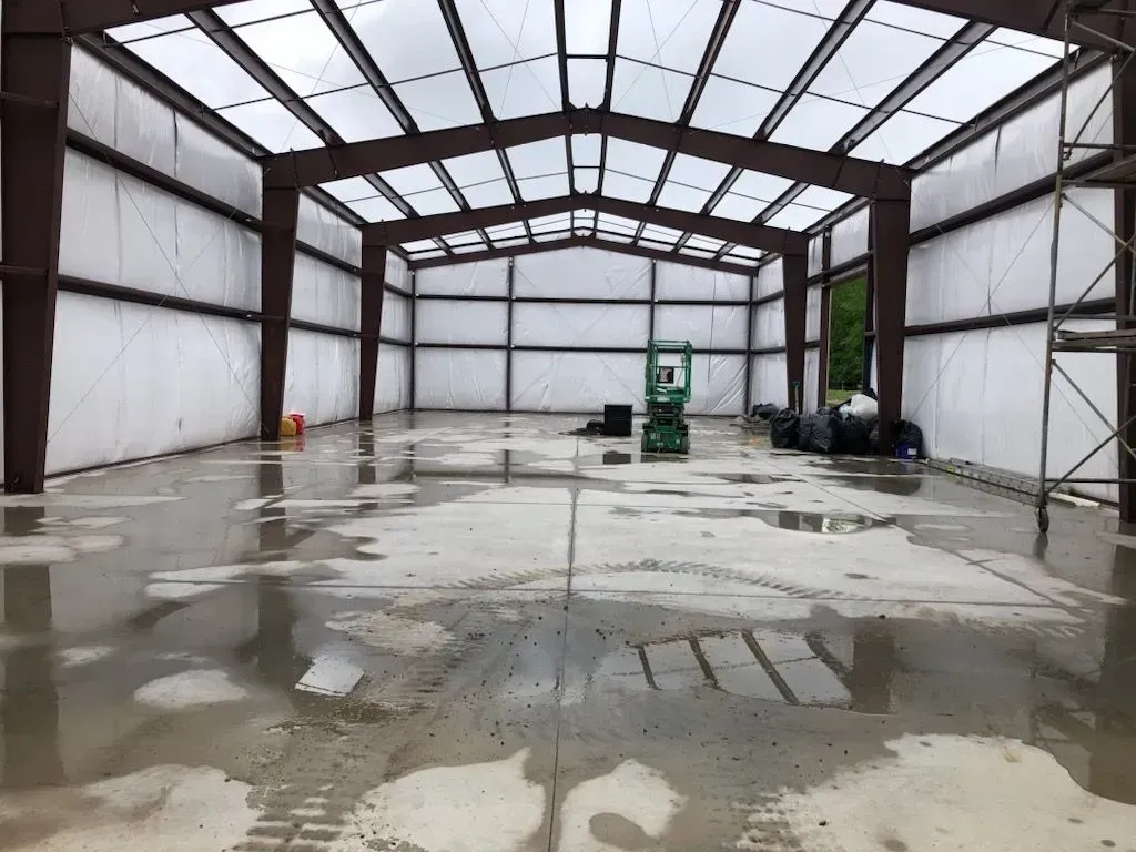 A large warehouse with a clear roof and a concrete floor.