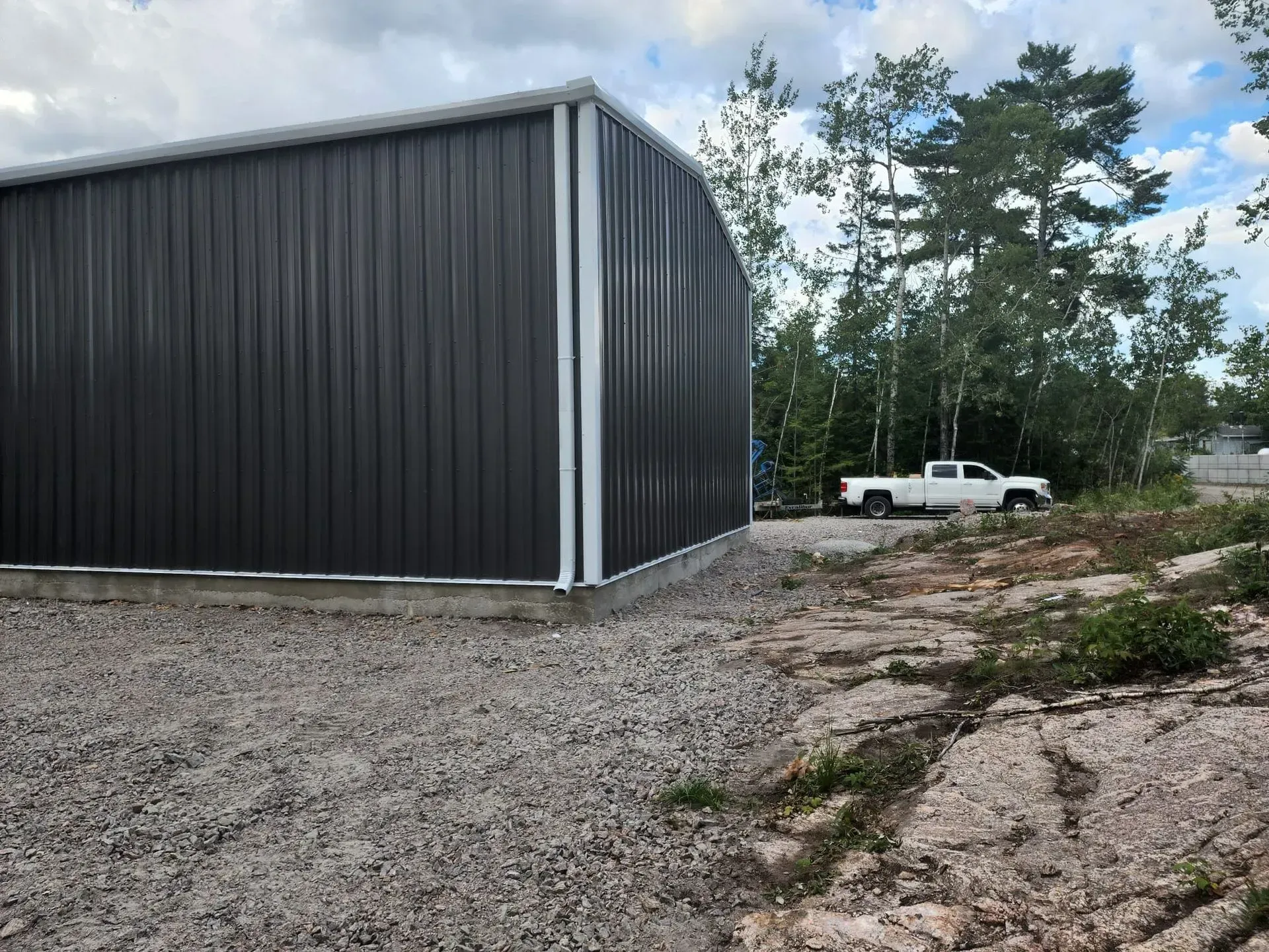 A white truck is parked in front of a large metal building.