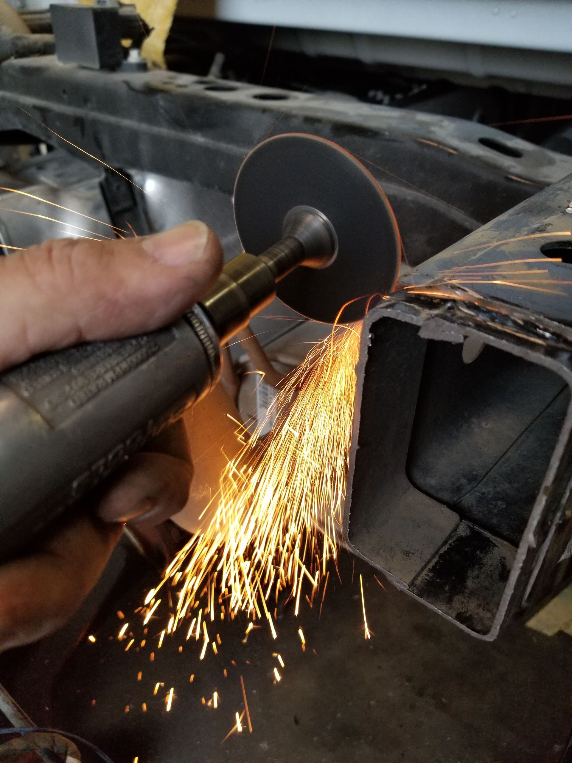 A person is using a grinder to cut a piece of metal