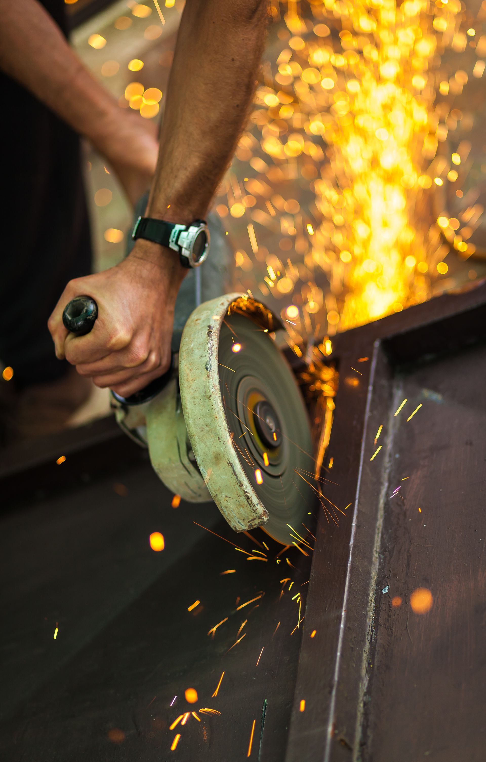 A man is using a grinder to cut a piece of metal.