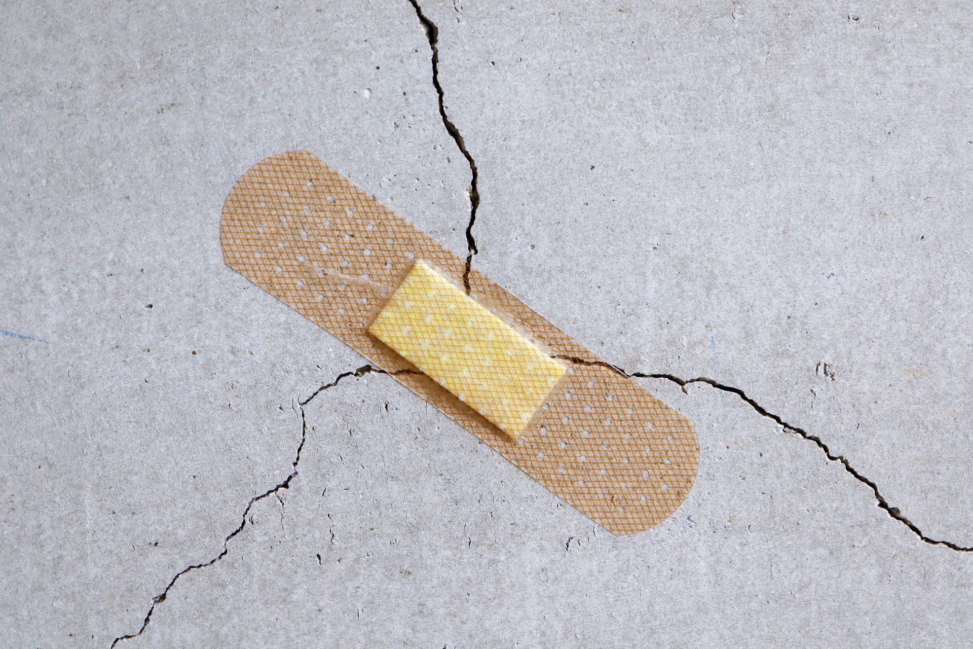 A bandage is sitting on a cracked concrete surface.
