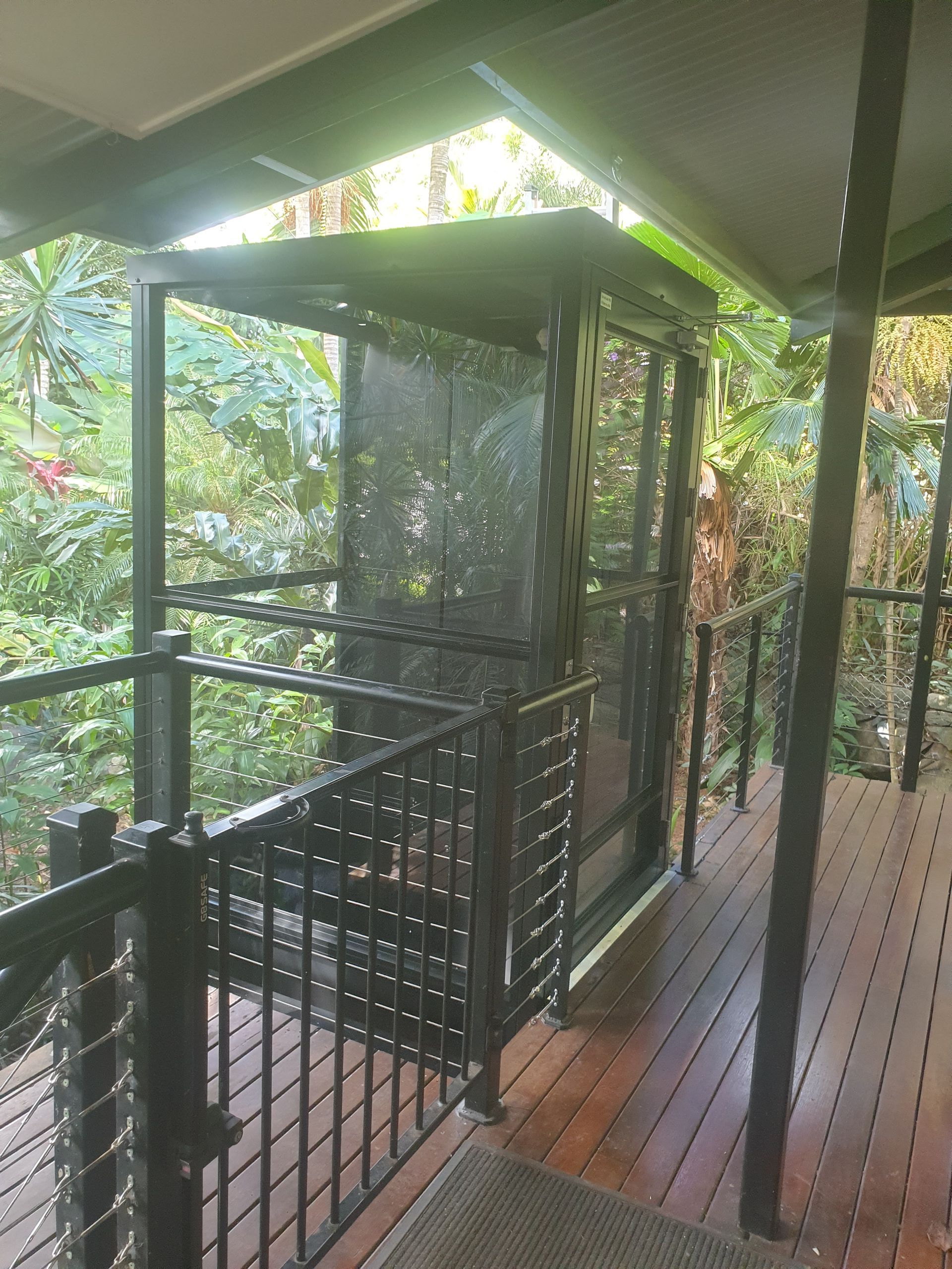 A Wooden Deck with A Black Railing and A Screen Door — Master Lifts Cairns in Cairns, QLD