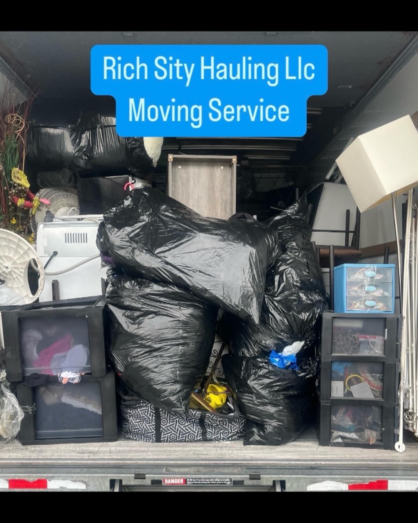 Packed moving truck with trash bags and bins, labeled “Rich Sity Hauling Llc Moving Service”