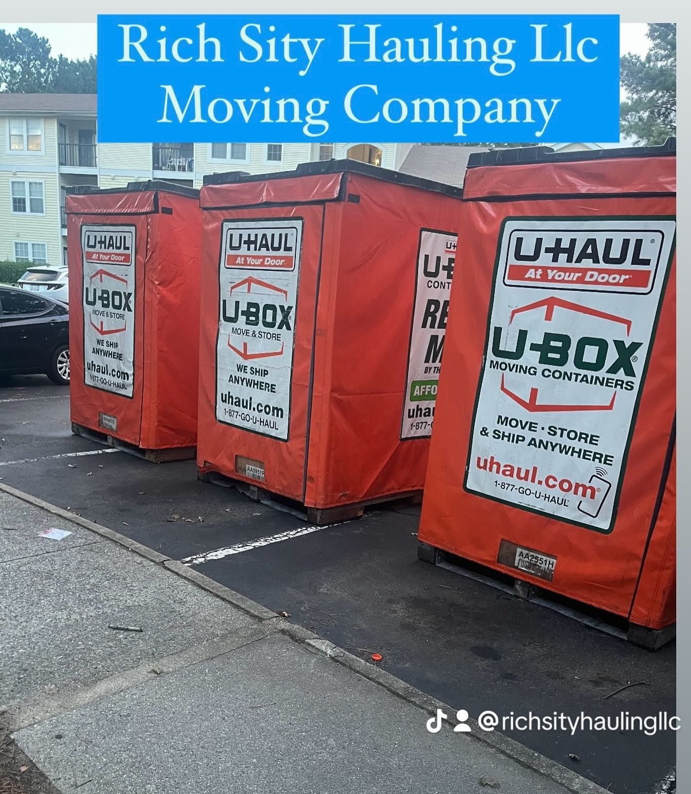 Three red U-Haul U-Box containers on a city sidewalk with a Rich City Hauling LLC moving company banner above