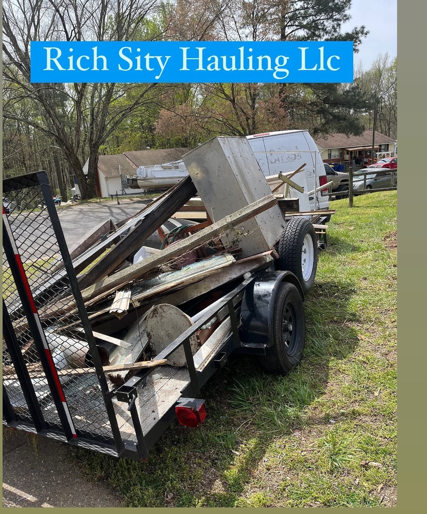 Trailer loaded with scrap metal and debris beside a fence, with a Rich City Hauling LLC sign above.