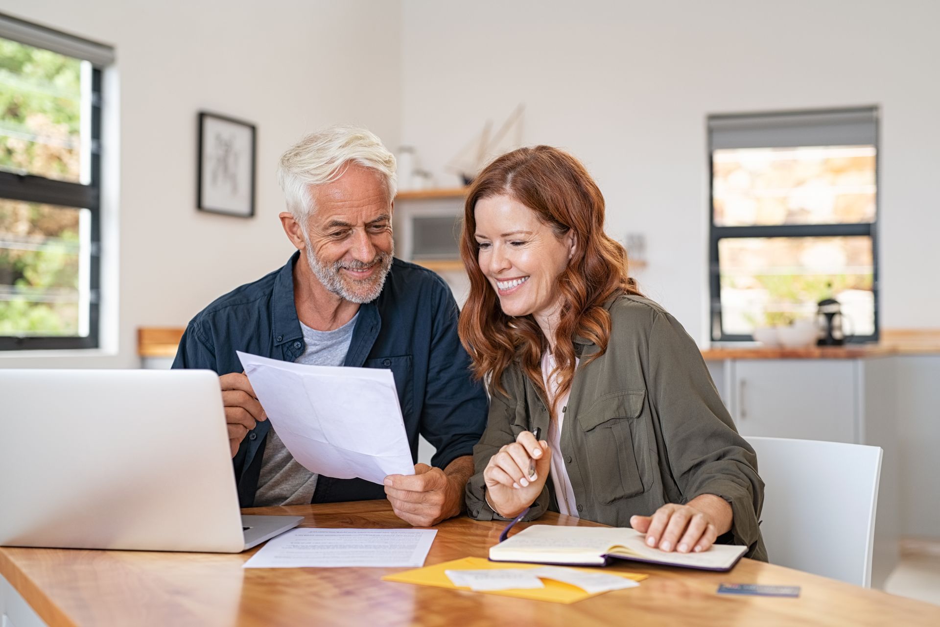 Real estate agent handing keys to a smiling couple after signing a contract.