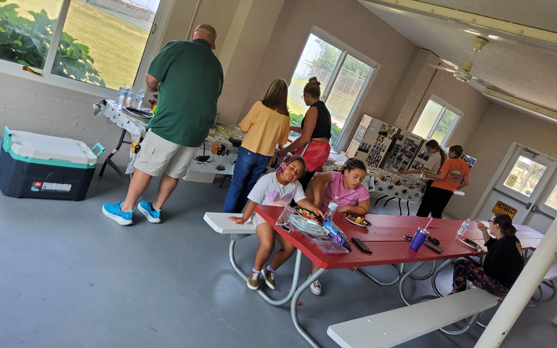 People gathered indoors at tables and counters, possibly crafting or working on a project.