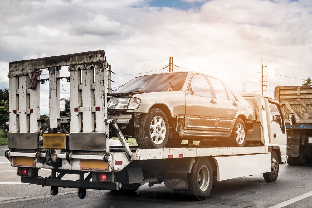 A Tow Truck is Carrying a Damaged Car on the Back of It — A & J Auto Body Repairs In Salamander Bay, NSW