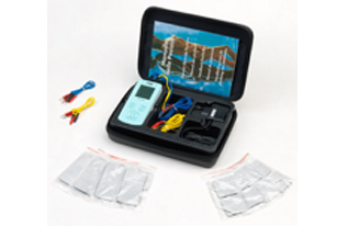 Kit di test aperto con misuratore digitale, cavi e due bustine argentate su sfondo bianco