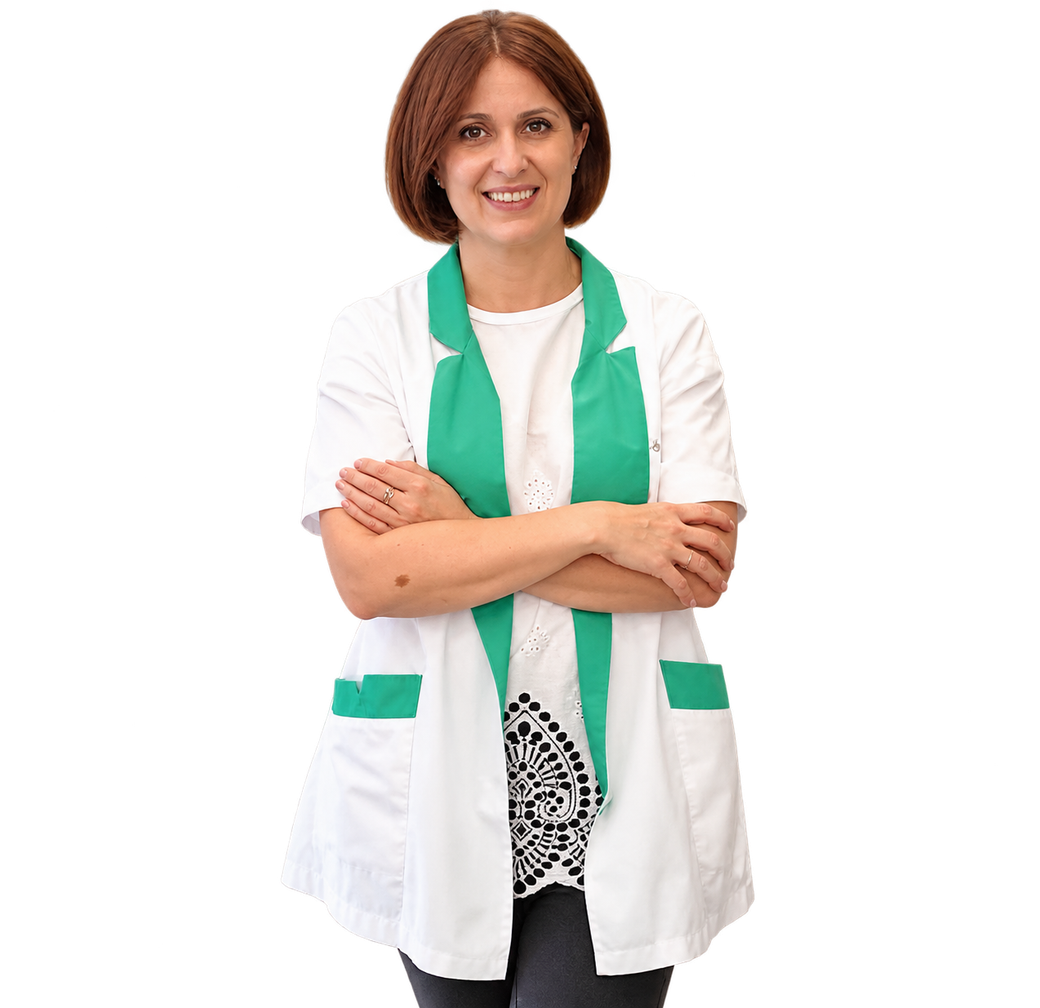 Persona sorridente con camice bianco e sciarpa verde, in piedi con le braccia incrociate su sfondo bianco.