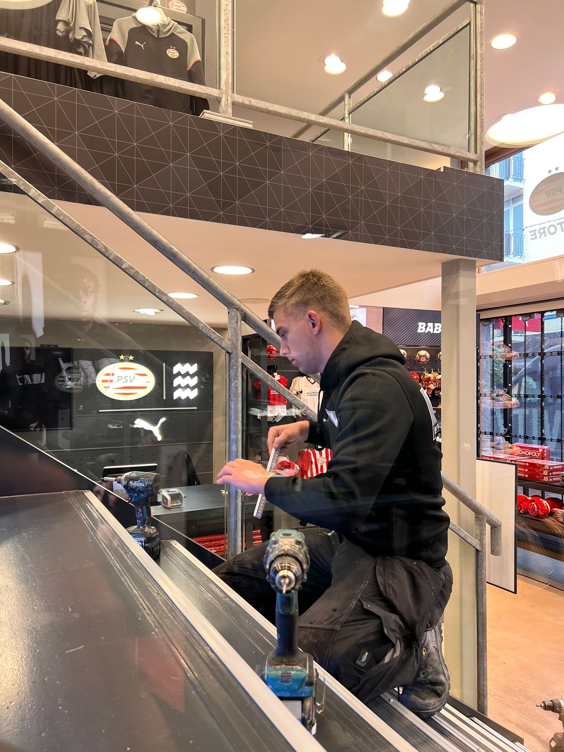 een man die een boormachine gebruikt in een winkel met een bord met de tekst bab