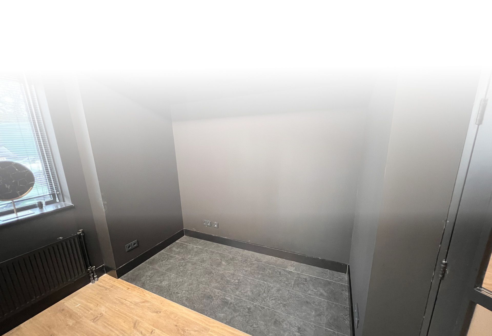 een lege kamer met een klok op de vensterbank