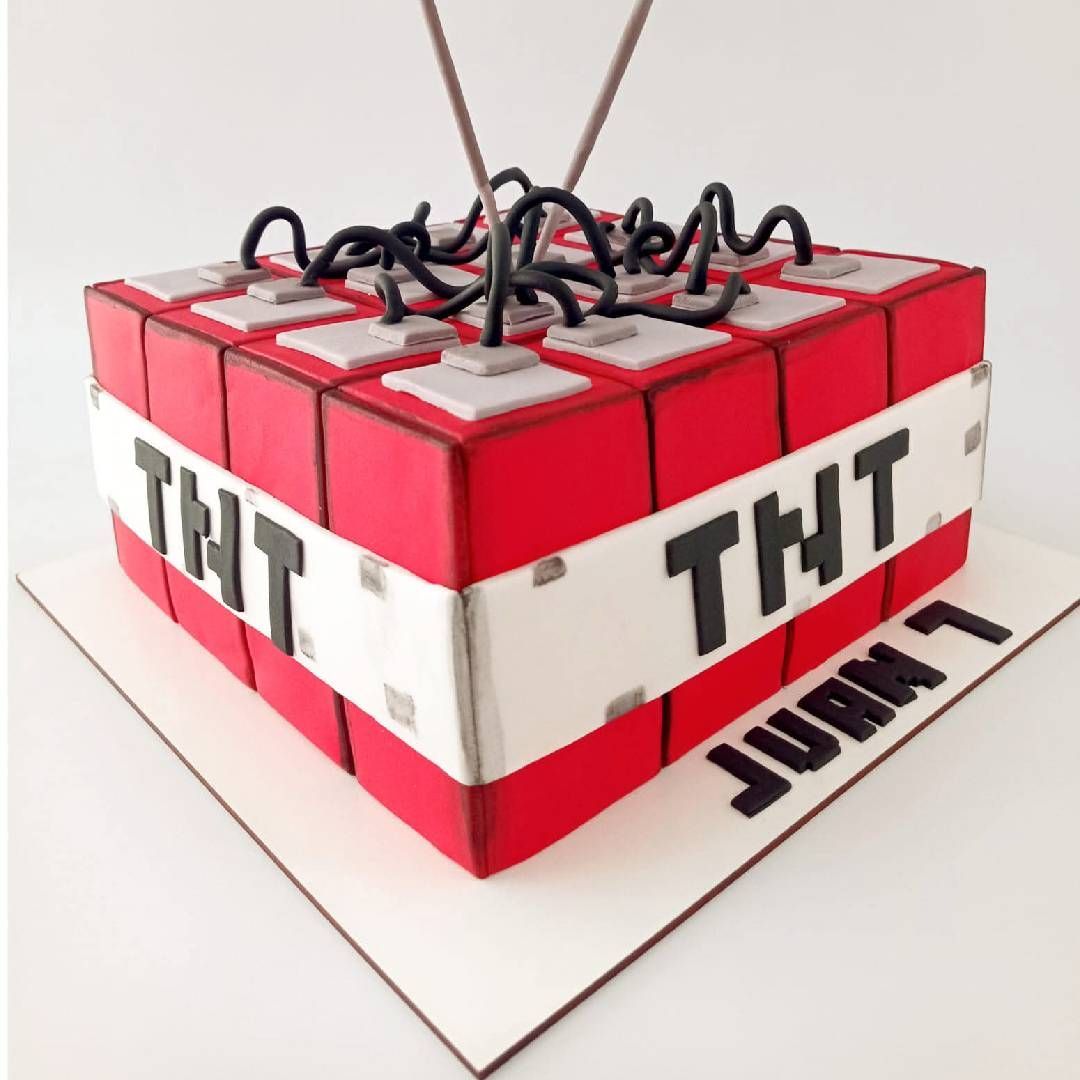 Caja de regalo roja con diseño de explosivo TNT, con cables negros y laterales blancos, colocada sobre una superficie blanca.