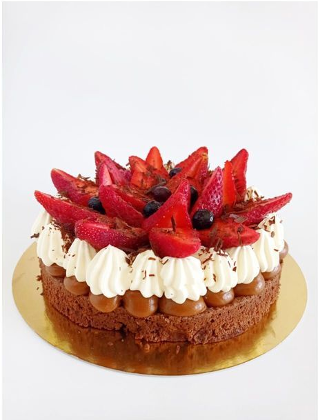 Pastel con fresas cubiertas con glaseado de crema batida sobre una base dorada.
