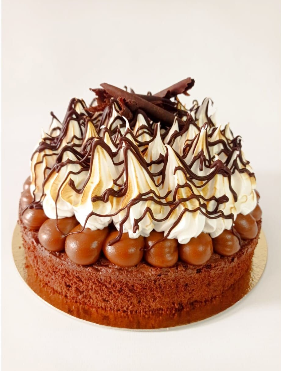 Pastel de chocolate cubierto con crema batida, sirope de chocolate y trocitos de chocolate.