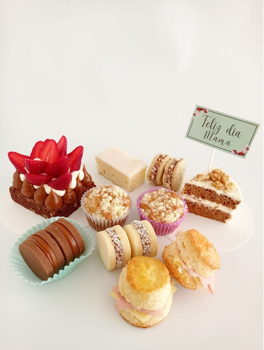 Variedad de pasteles y postres sobre una superficie blanca con una pequeña tarjeta identificativa.