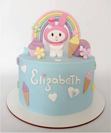 Tarta de cumpleaños en tonos pastel con decoraciones de conejito y arcoíris, etiquetada como 
