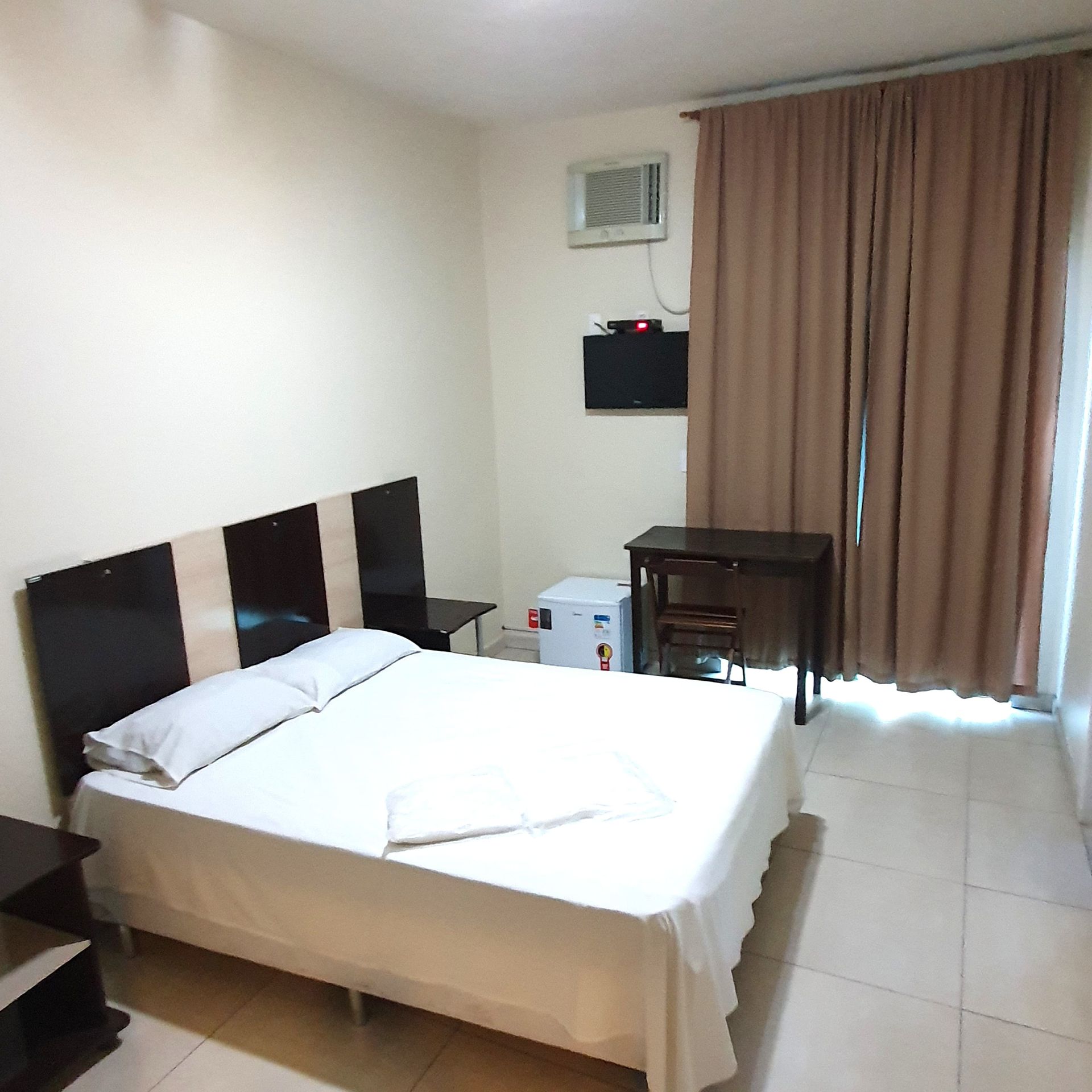 Um quarto de hotel com uma cama grande e uma escrivaninha