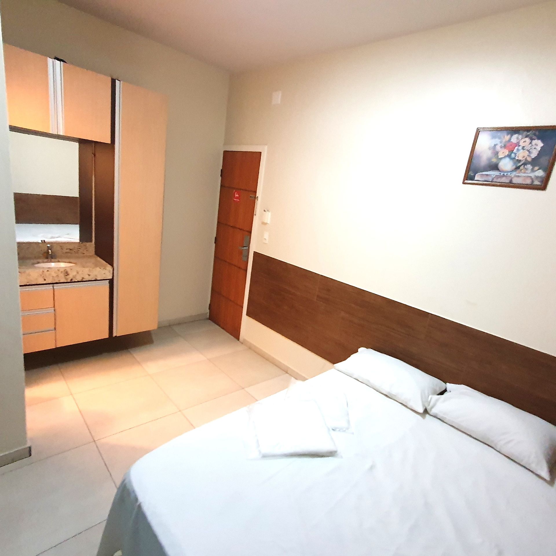 Um quarto com uma cama, uma pia e um quadro na parede