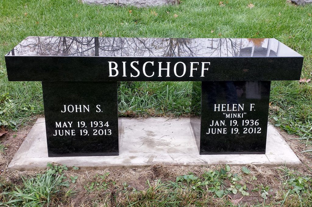 Black gravestone engraved “BISCHOFF” with two name plaques in a grassy cemetery