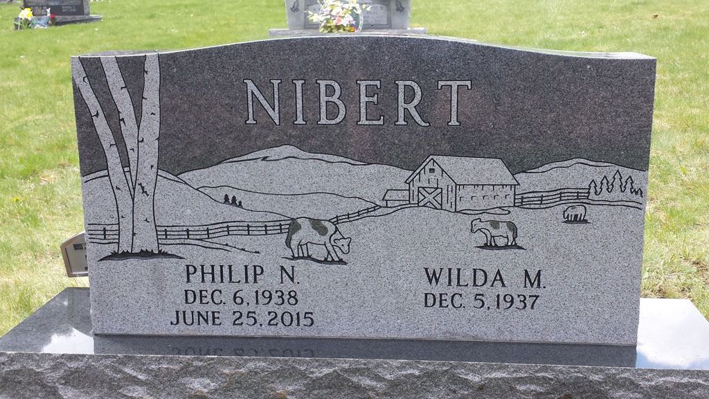 Gray gravestone engraved “NIBERT” with rural scene and two names and dates at the bottom