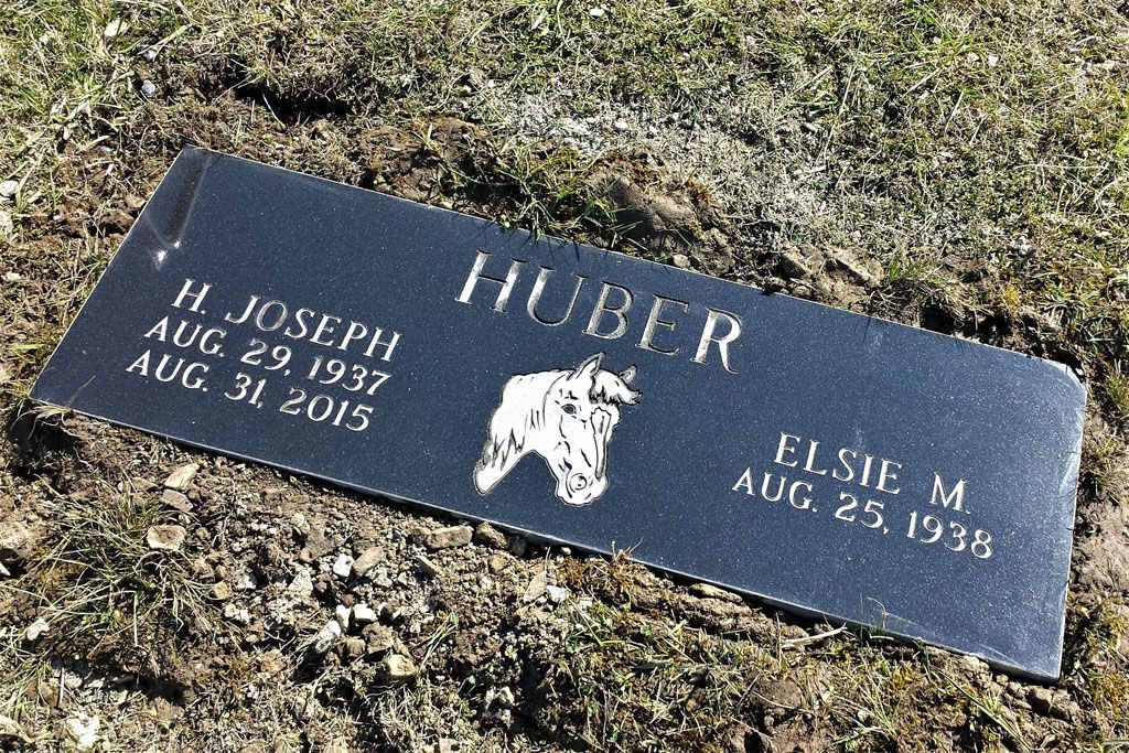 Granite gravestone with “HUBER” and engraved names on a grassy cemetery plot