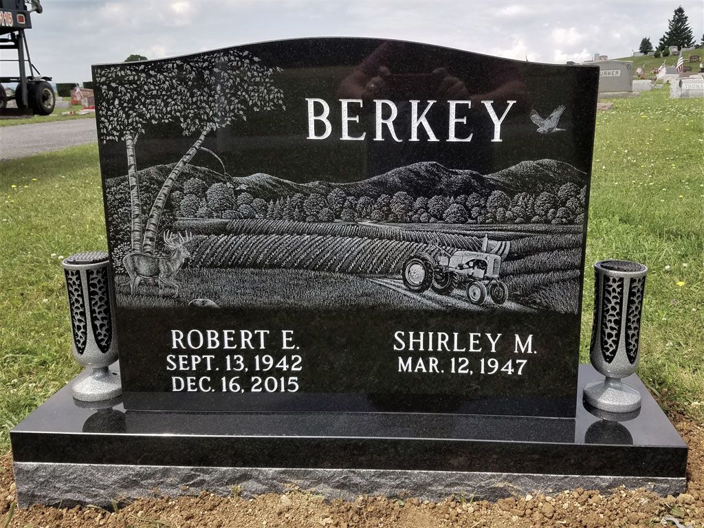 Black granite Berkey gravestone with white engraved names and dates in a cemetery.