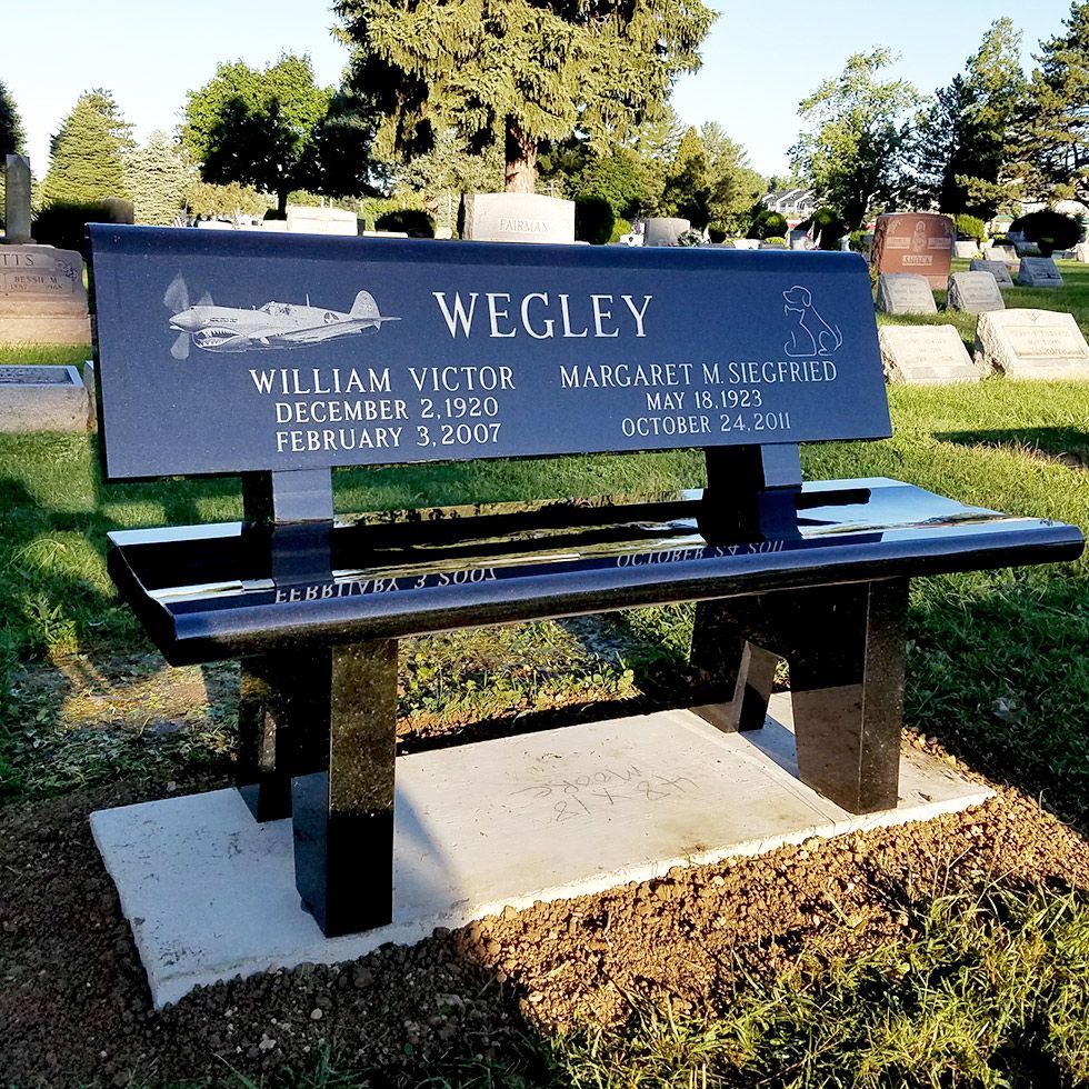 Blue memorial bench in a cemetery with the name “Wegley” on the backrest