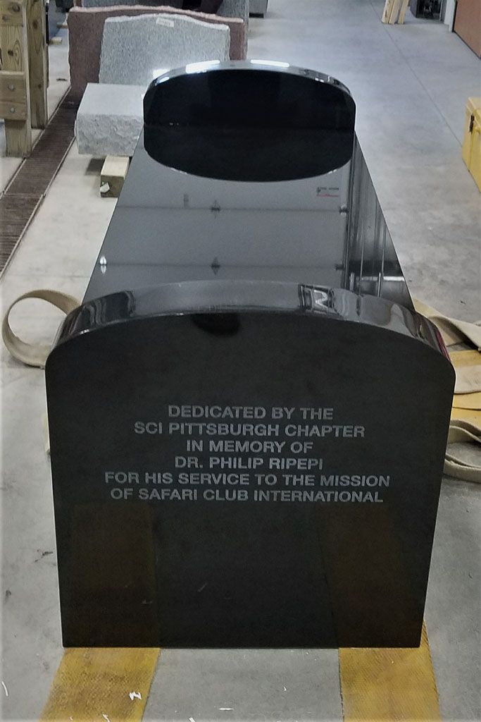 Black memorial plaque or monument with engraved text in an outdoor setting