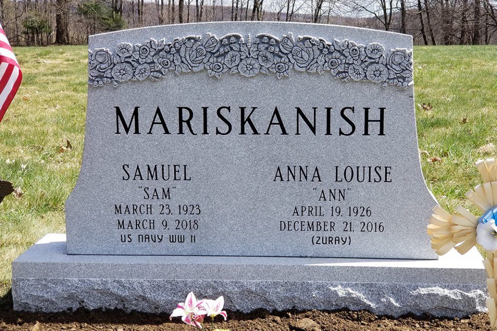Mariskanish gravestone with two names and dates in a grassy cemetery